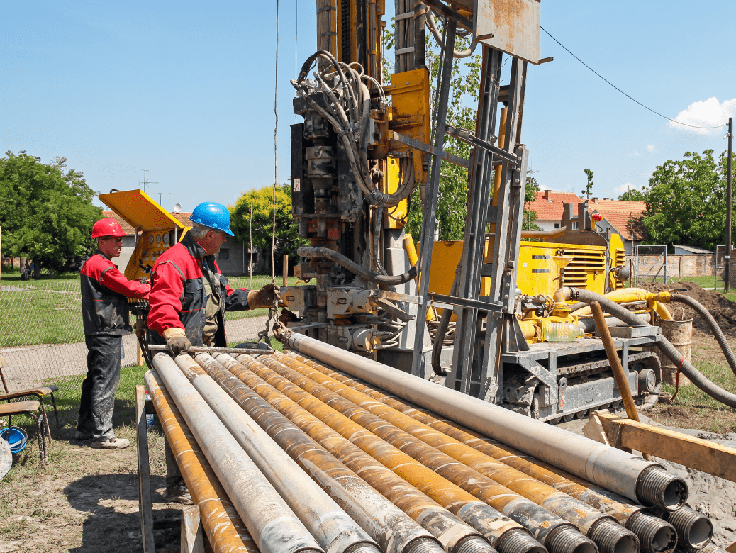 Workers operating a drilling machine outdoors